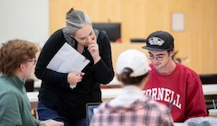 A teacher looks over the shoulder of a student wearing a "Cornell" sweatshirt