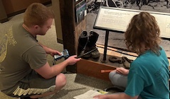 Two students use a tool to analyze an artifact.
