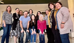 A group of people gather together looking at the camera.