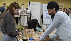 Two students look at a table at a science fair.