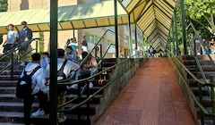 Students with backpacks walk up a staircase on a college campus.